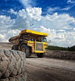 A yellow dumper truck drives down a road